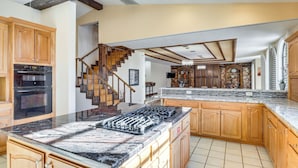 A spacious kitchen with granite countertops, wooden cabinets, and a built-in stove.