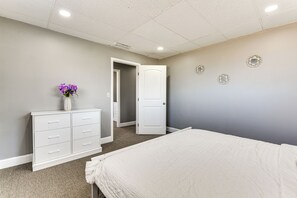 Un dormitorio con cama, cómoda y puerta que da a otra habitación.