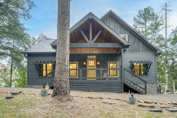 A lodge with a prominent front porch, a staircase leading to the entrance, and a large tree in the foreground.