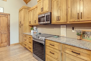 A kitchen with wooden cabinets, a stainless steel microwave, a gas stove, and a built-in oven.