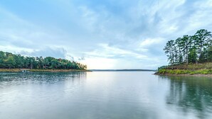 A calm lake with clear water, surrounded by dense forest and a distant shoreline. - Lake Views & Golf Access at Secluded Drasco Lodge (Drasco)