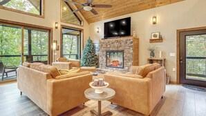 A spacious living room with a fireplace, leather sofas, a television, and a ceiling fan. - Lake Views & Golf Access at Secluded Drasco Lodge (Drasco)