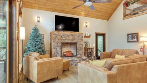 A cozy living room with a stone fireplace, leather sofas, a television, and a Christmas tree. - Lake Views & Golf Access at Secluded Drasco Lodge (Drasco)