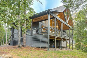 Une cabane avec une façade en bois, de nombreuses fenêtres et une terrasse.