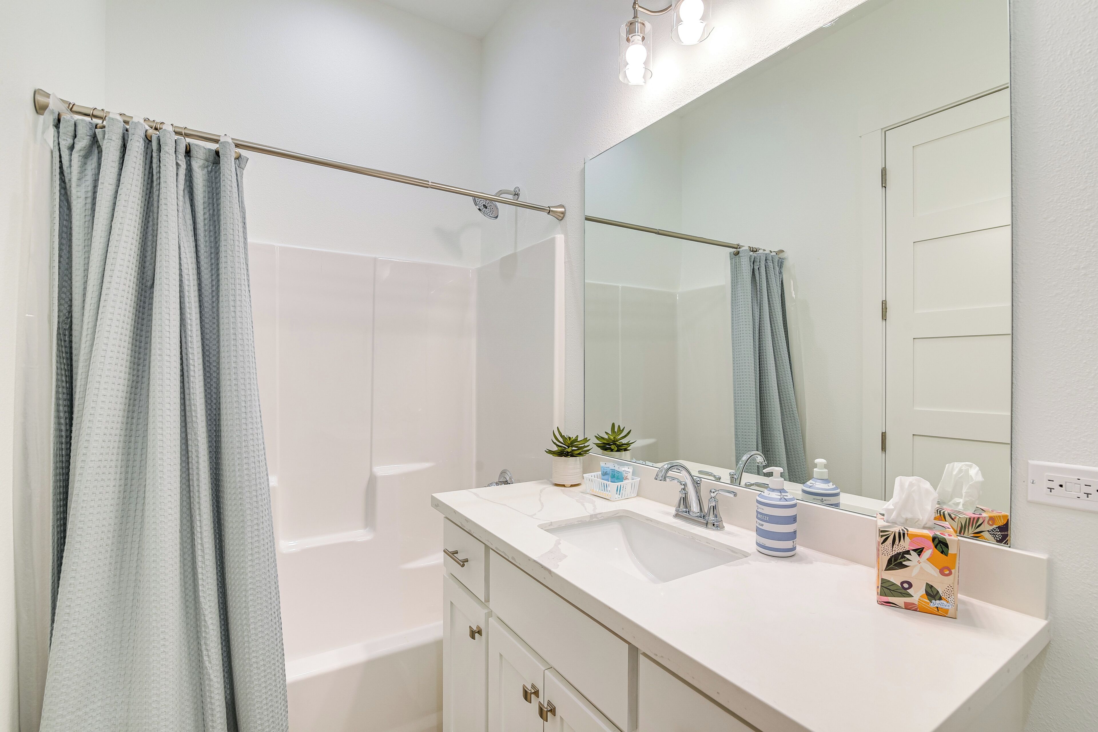 A bathroom with a bathtub, a sink, a mirror, and a shower curtain.