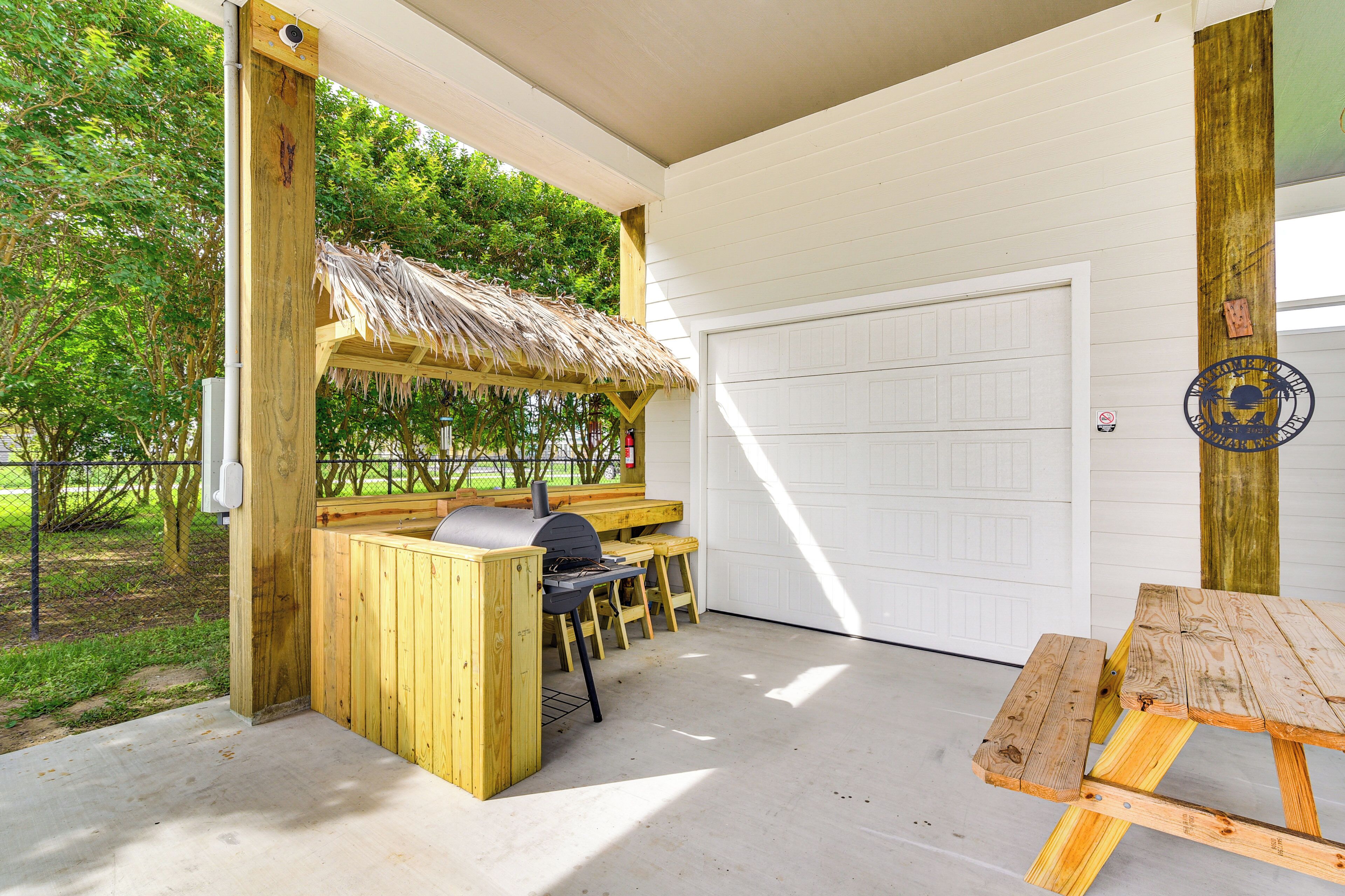 An outdoor wooden structure with a grill, seating, and a table.