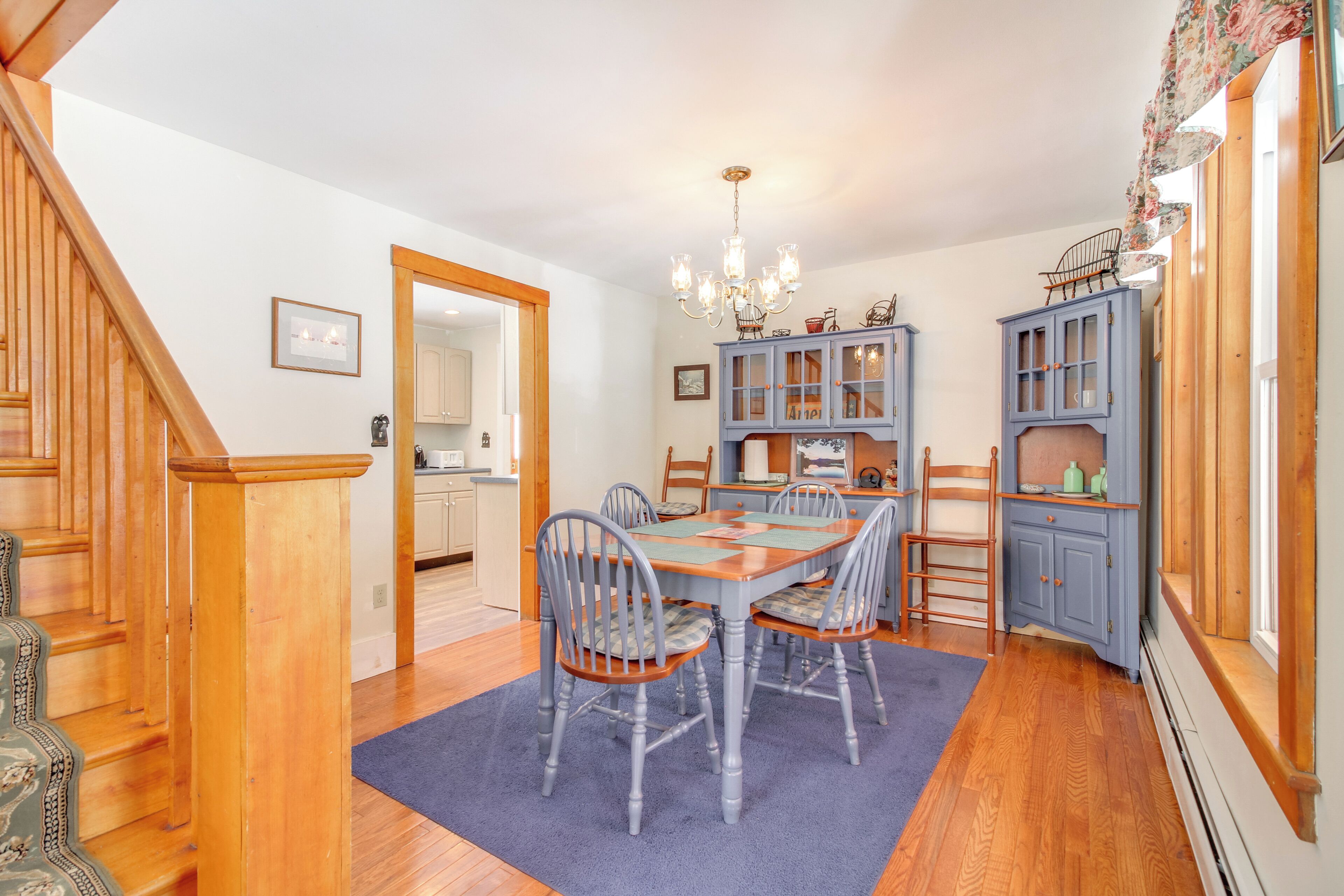 A dining area with a wooden table and chairs, a chandelier, and blue cabinets.
