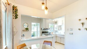 A modern kitchen with white cabinets, a glass dining table, and pendant lighting. - 3 Mi to Universal Studios: Chic Home w/ Yard! (Burbank)