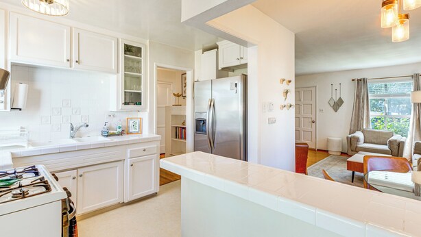 A modern kitchen with white cabinetry, a stainless steel refrigerator, and a central island. - 3 Mi to Universal Studios: Chic Home w/ Yard! (Burbank)
