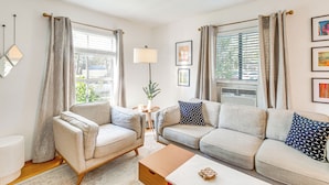 A living room with a beige sofa, a matching armchair, a wooden coffee table, and a small side table with a lamp. - 3 Mi to Universal Studios: Chic Home w/ Yard! (Burbank)