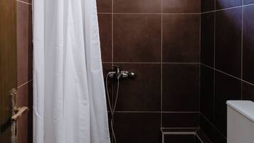 Une salle de bain avec une douche, des toilettes et un petit tabouret.