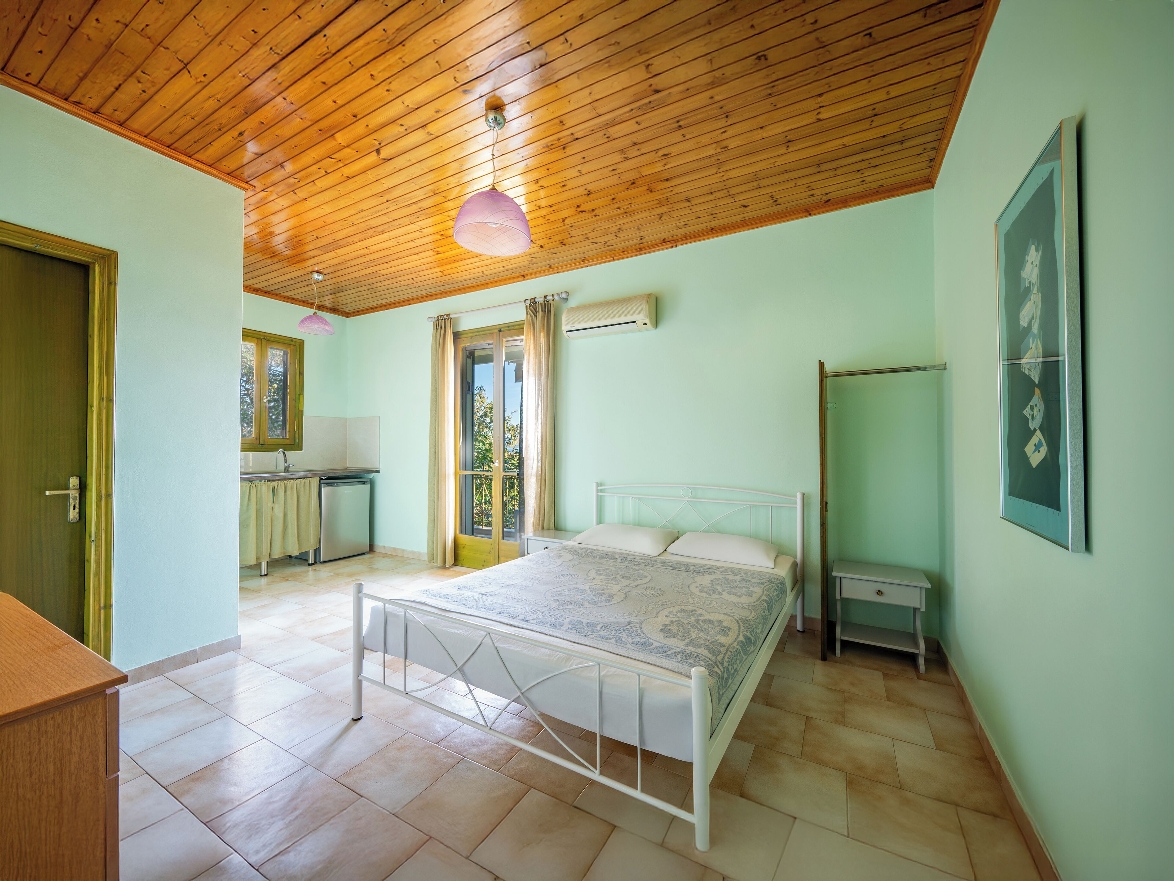 A bedroom with a bed, a desk, and a window.