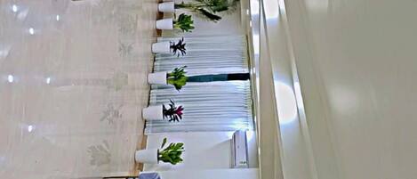 A spacious, modern lounge area with a sofa set, a dining table, and potted plants.