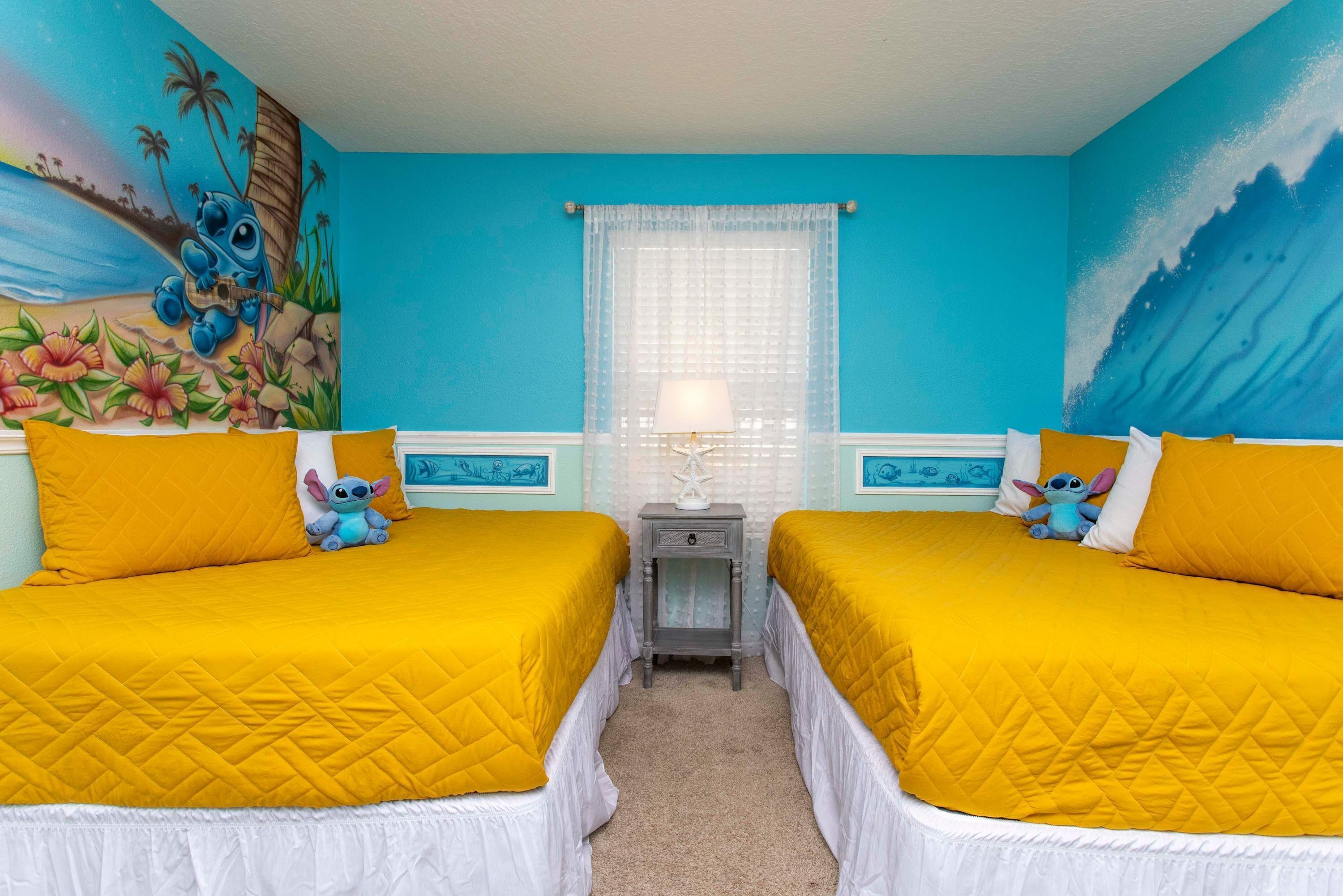 Una habitación con dos camas, cada una con colcha amarilla, una mesita de noche con lámpara, y un mural de Stitch de Lilo & Stitch.