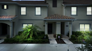 A two-story residential building with a tiled roof, a covered front porch, and a well-maintained garden with a palm tree. - Wonderful 4Bd With Pool at Storey Lake Resort 4819 (Kissimmee)