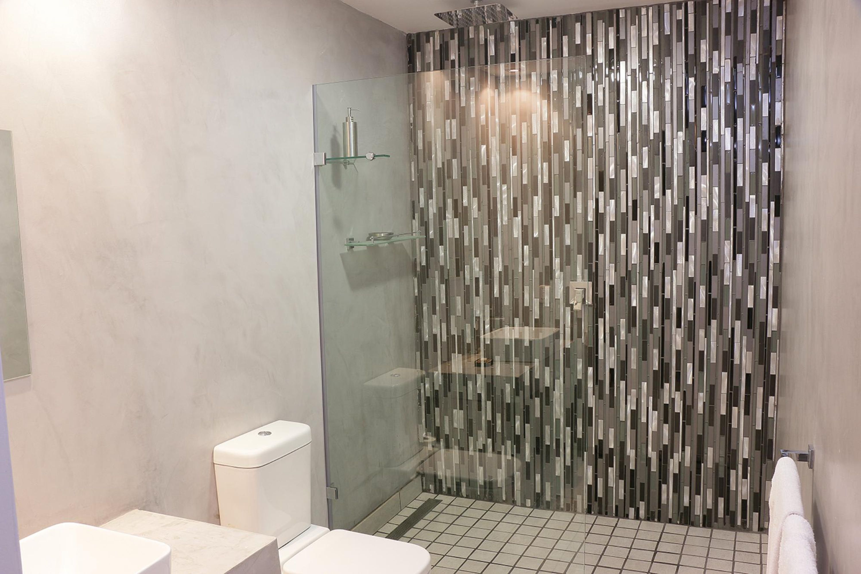 Un bagno moderno con doccia vetro, un water e un lavandino.