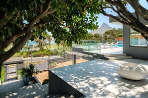 A modern outdoor area with a pool, lounge chairs, and a large white planter.