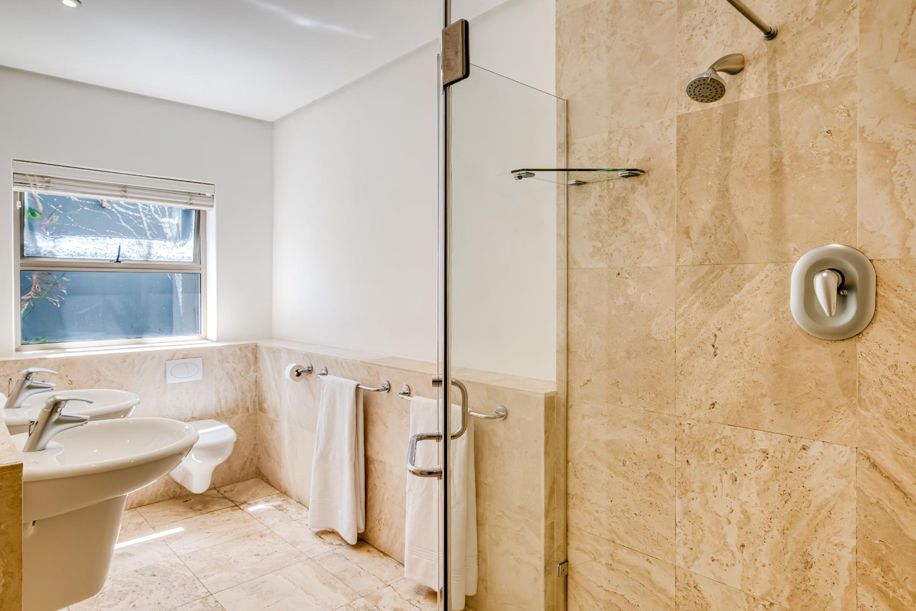 A modern bathroom with a glass-enclosed shower, a toilet, and a sink.