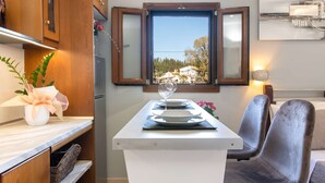 Ein Essbereich mit Tisch für zwei Personen, einem Fenster mit Blick auf eine verschneite Landschaft und einer Vase mit Blumen auf der Arbeitsplatte.