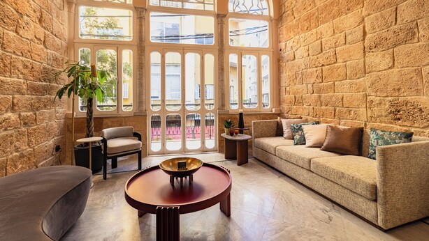 A cozy living room with a stone wall, a sofa, a round table, and a chair. - Canvas Boutique Hotel  (Beirut)