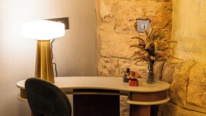 A corner room with a desk, chair, lamp, vase with flowers, and a patterned bedspread. - Canvas Boutique Hotel  (Beirut)