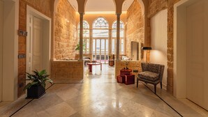 A spacious hallway with stone walls, arched windows, and a central seating area with a table and chairs. - Canvas Boutique Hotel  (Beirut)