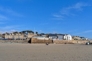 A coastal town with stone buildings, a sandy beach, and a clear blue sky.
