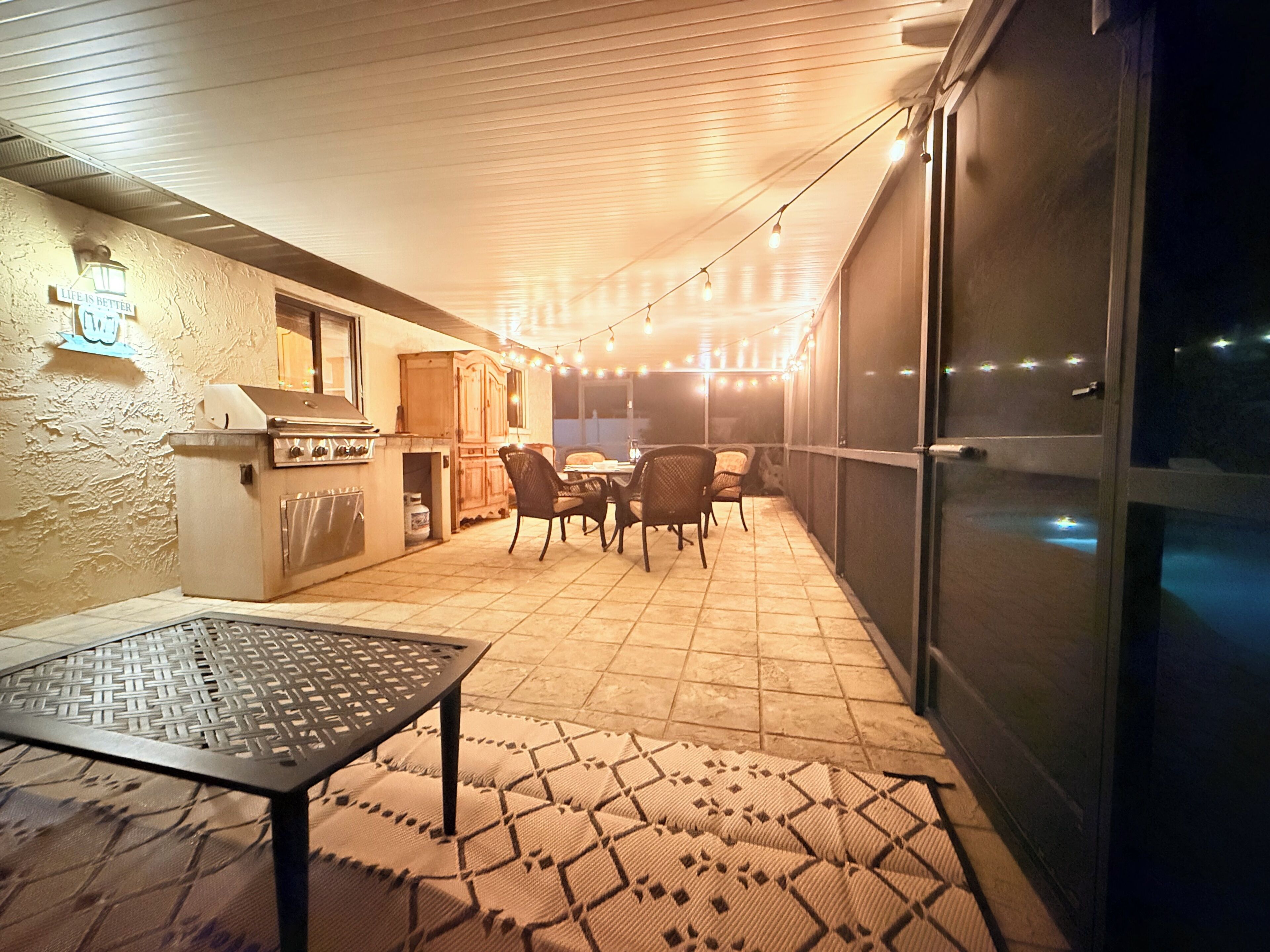 Un patio al aire libre con una parrilla, sillas y una mesa.