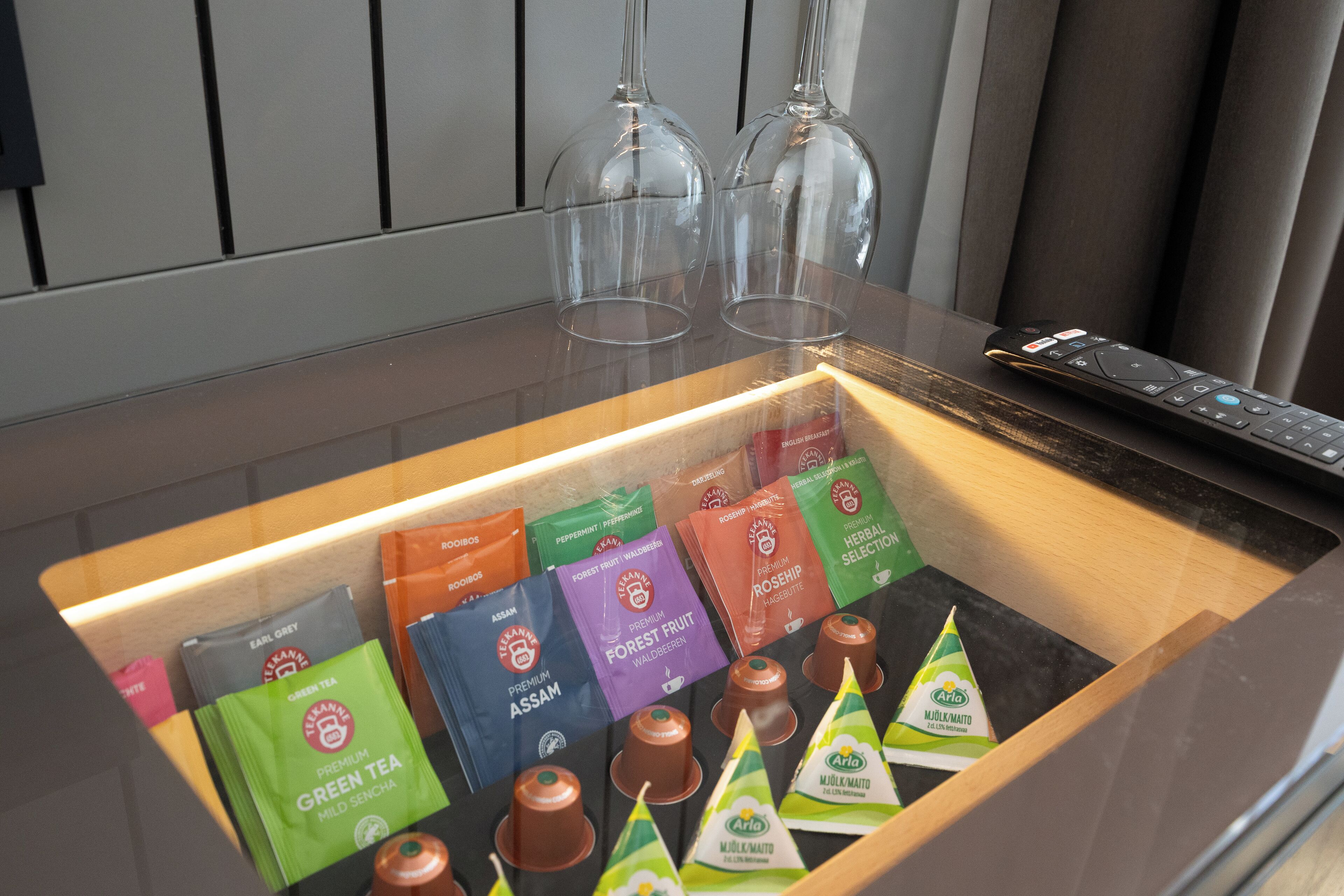 Una presentación de bolsitas de té y un control remoto sobre una encimera.