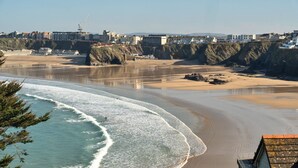 A coastal view with a beach, cliffs, and buildings in the background.