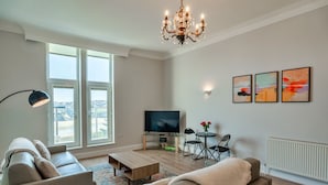 A modern living room with a sofa, coffee table, TV, and artwork on the wall.