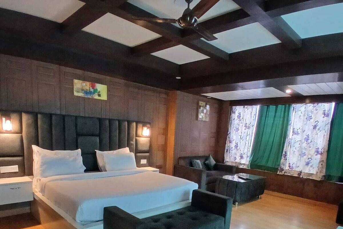 A spacious bedroom with a large bed, a sofa, a desk, and a ceiling fan.