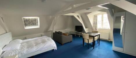 A room with a bed, a sofa, a dining table, and a TV.
