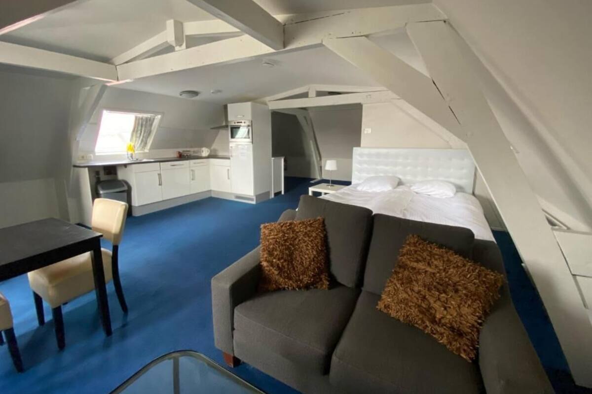 A compact, modern room with a sofa, a small dining table, and a kitchenette.