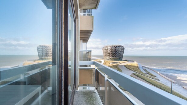 A modern building with a glass balcony overlooking a beach and two spherical structures. - Family Spot by the Coastal Trails (Middelkerke)