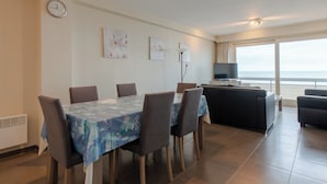 A dining area with a table set for six, a sofa, and a TV. - Family Spot by the Coastal Trails (Middelkerke)