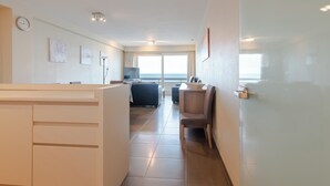 A modern hotel room with a kitchen area, a dining table, and a large window offering a view of the sea. - Family Spot by the Coastal Trails (Middelkerke)