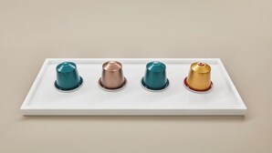 A white tray with four metallic cups in teal, copper, and gold colors.