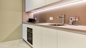 Une cuisine moderne avec des meubles blancs, une cuisinière noire, un évier et une machine à café.