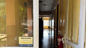 Un pasillo de hotel con un extintor, un letrero que indica pago con Visa y una puerta de vidrio con el logotipo de HOTSPOT.