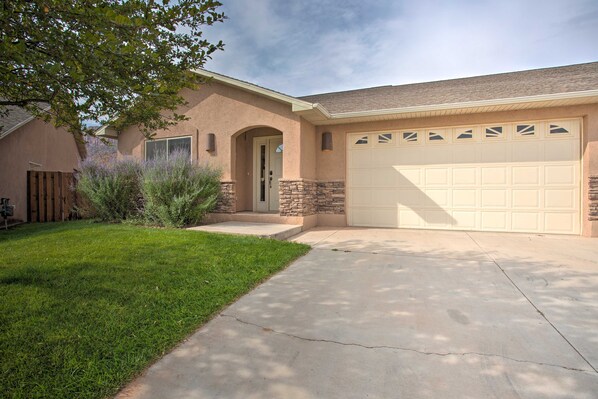 A residential house with a garage, a front door, and a well-maintained lawn. - 3444 Views, Garage and backyard, Shared Pool and Hot Tub! (Moab)