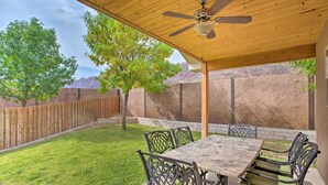 An outdoor patio with a wooden ceiling, a table with chairs, and a view of a mountain range. - 3444 Views, Garage and backyard, Shared Pool and Hot Tub! (Moab)