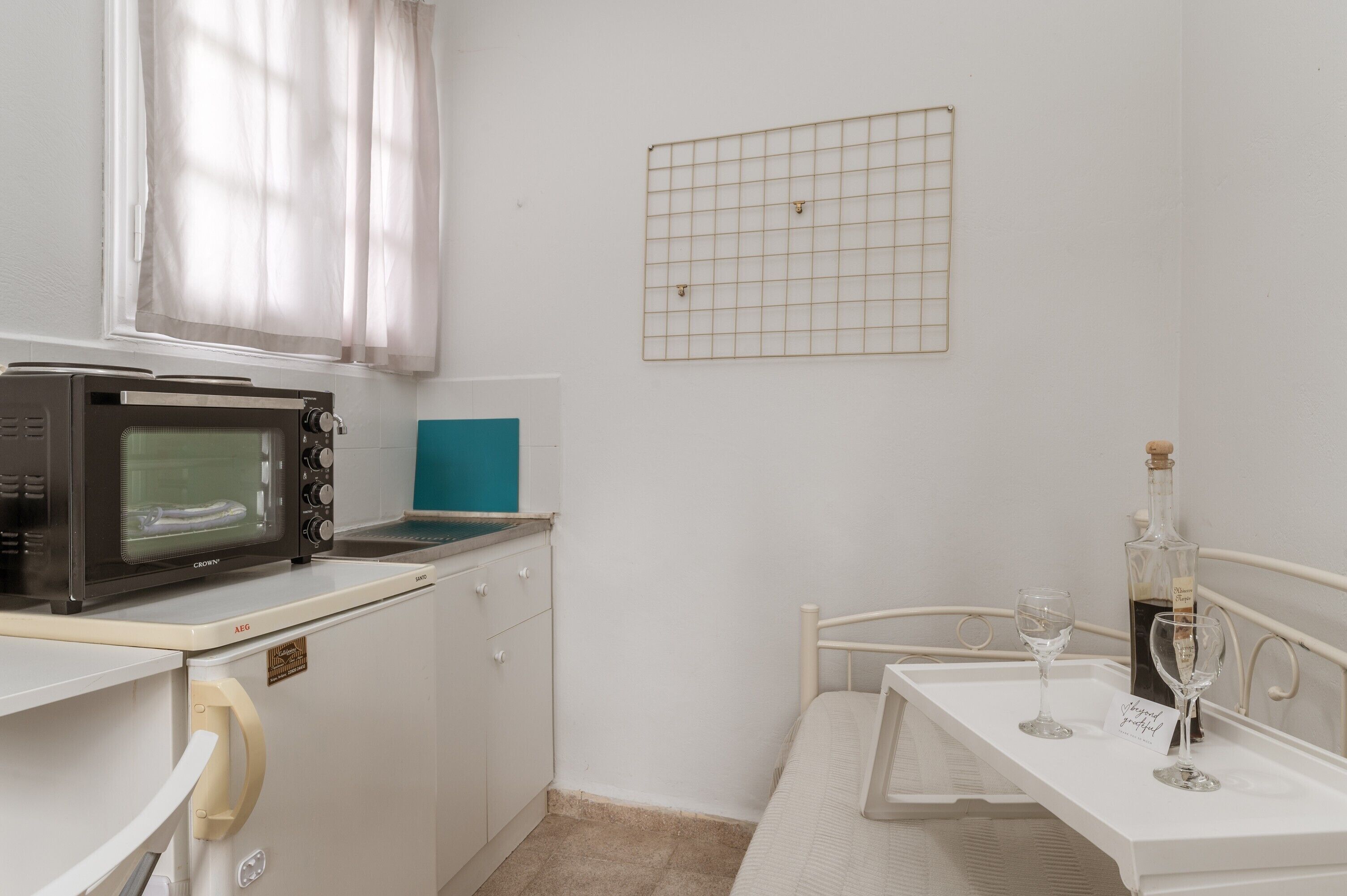 A compact kitchenette with a microwave, a small sink, and a window with curtains.