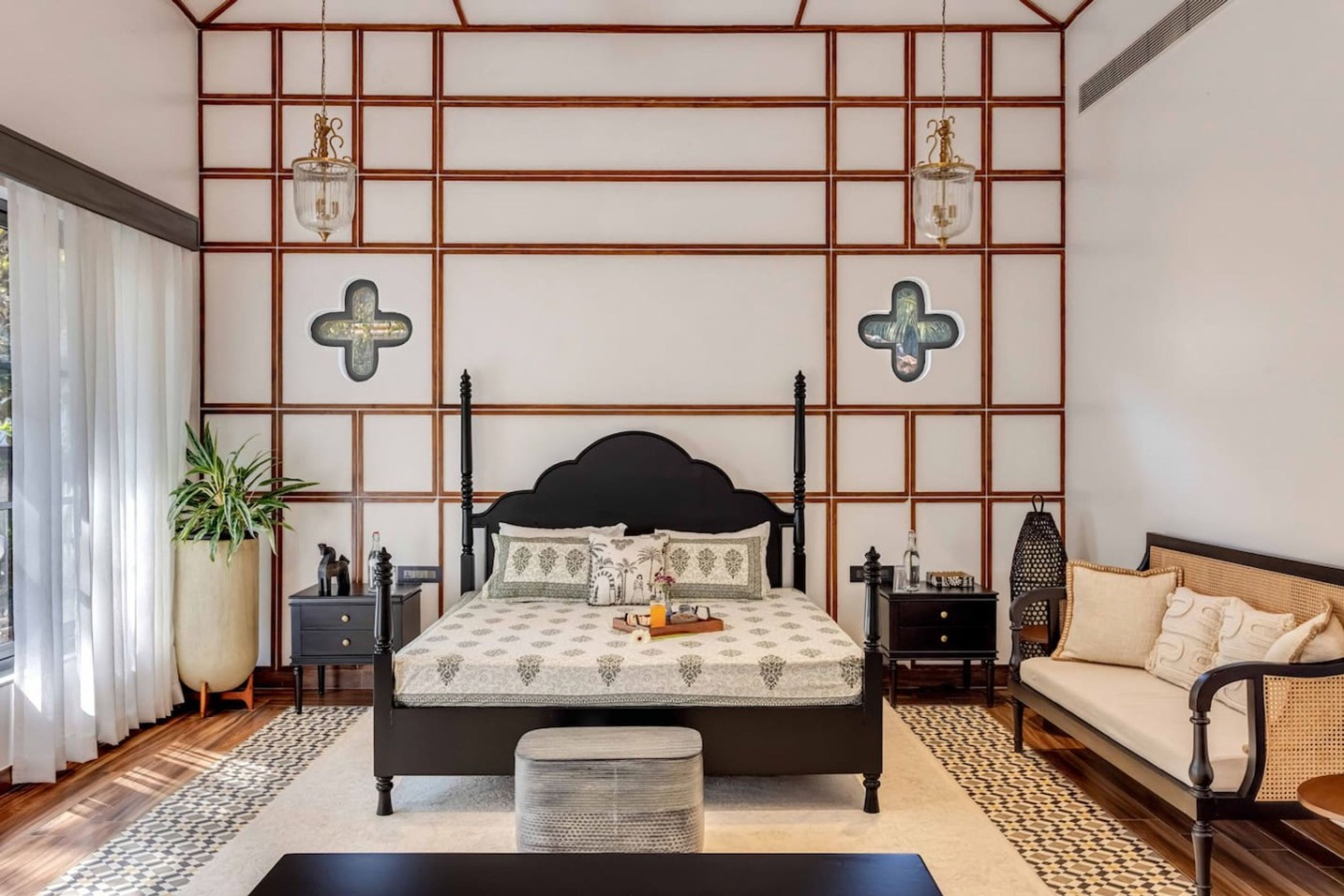 A bedroom with a bed, bedside tables, a sofa, and a large window with curtains.