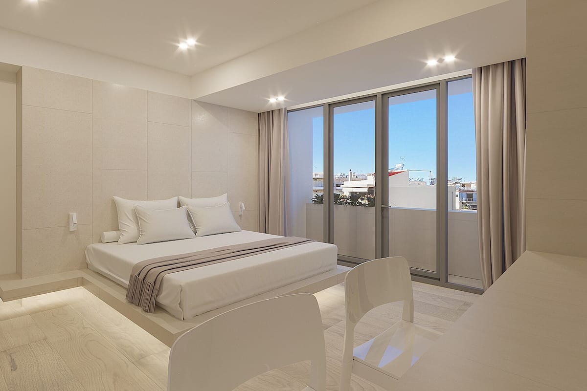 A modern hotel room with a large bed, a balcony with a city view, and a minimalist design.