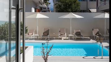 Una piscina al aire libre, sombrillas, tumbonas