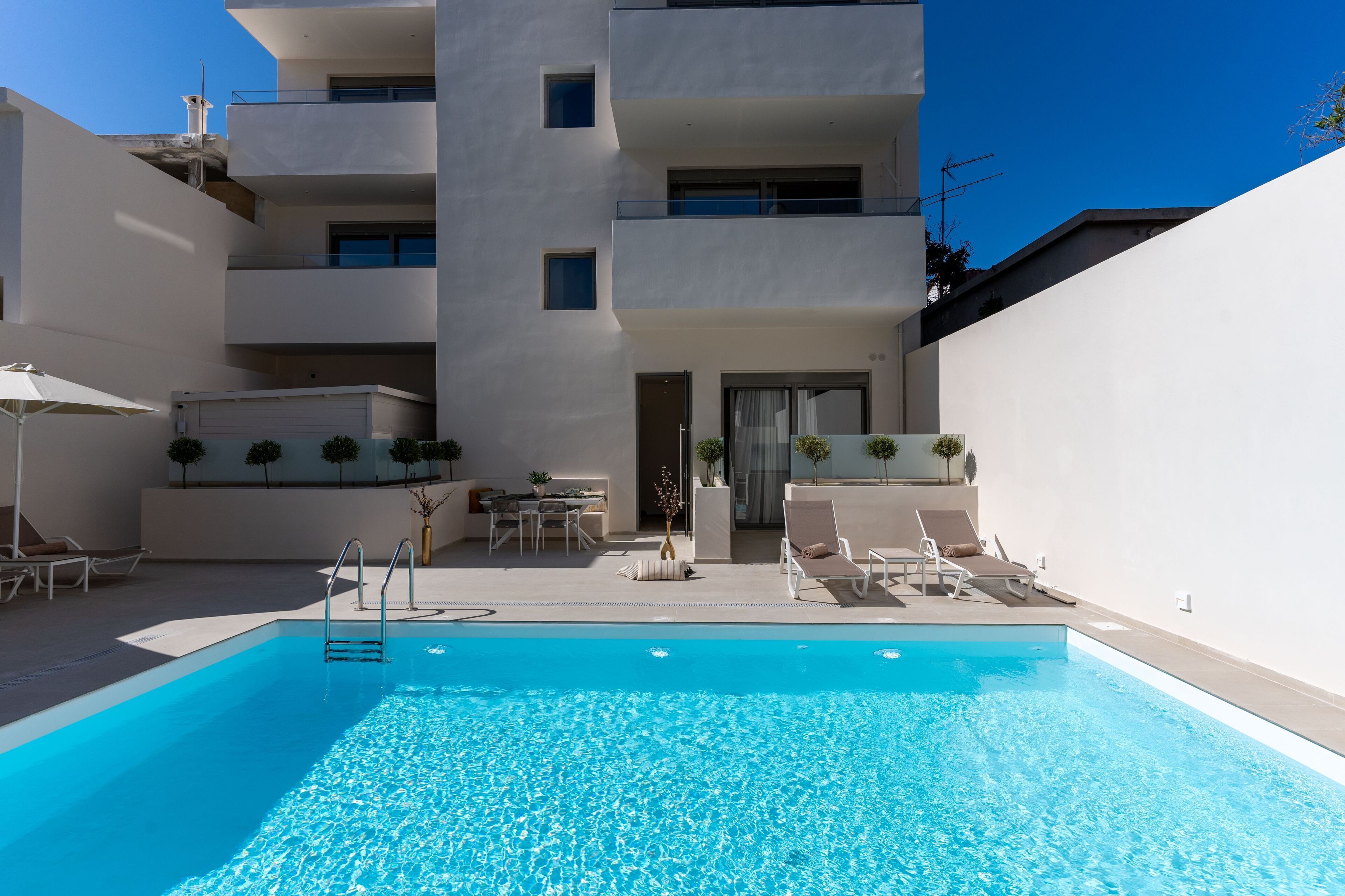 Una piscina al aire libre, sombrillas, sillones reclinables de piscina