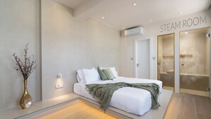 A modern steam room with a bed, a vase with dried flowers, and a sign indicating the room's purpose. - Selected Suites  (Chania)