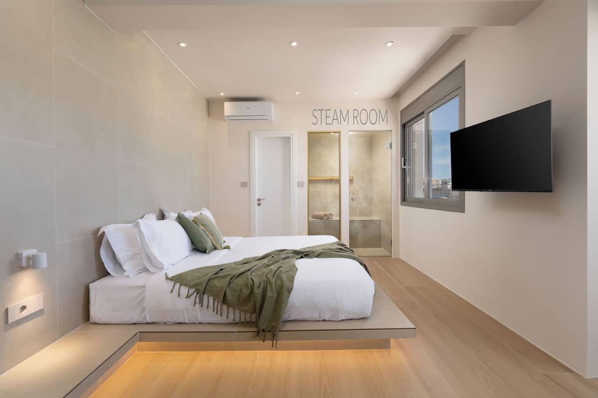 A modern bedroom with a bed, a TV, and a steam room sign.