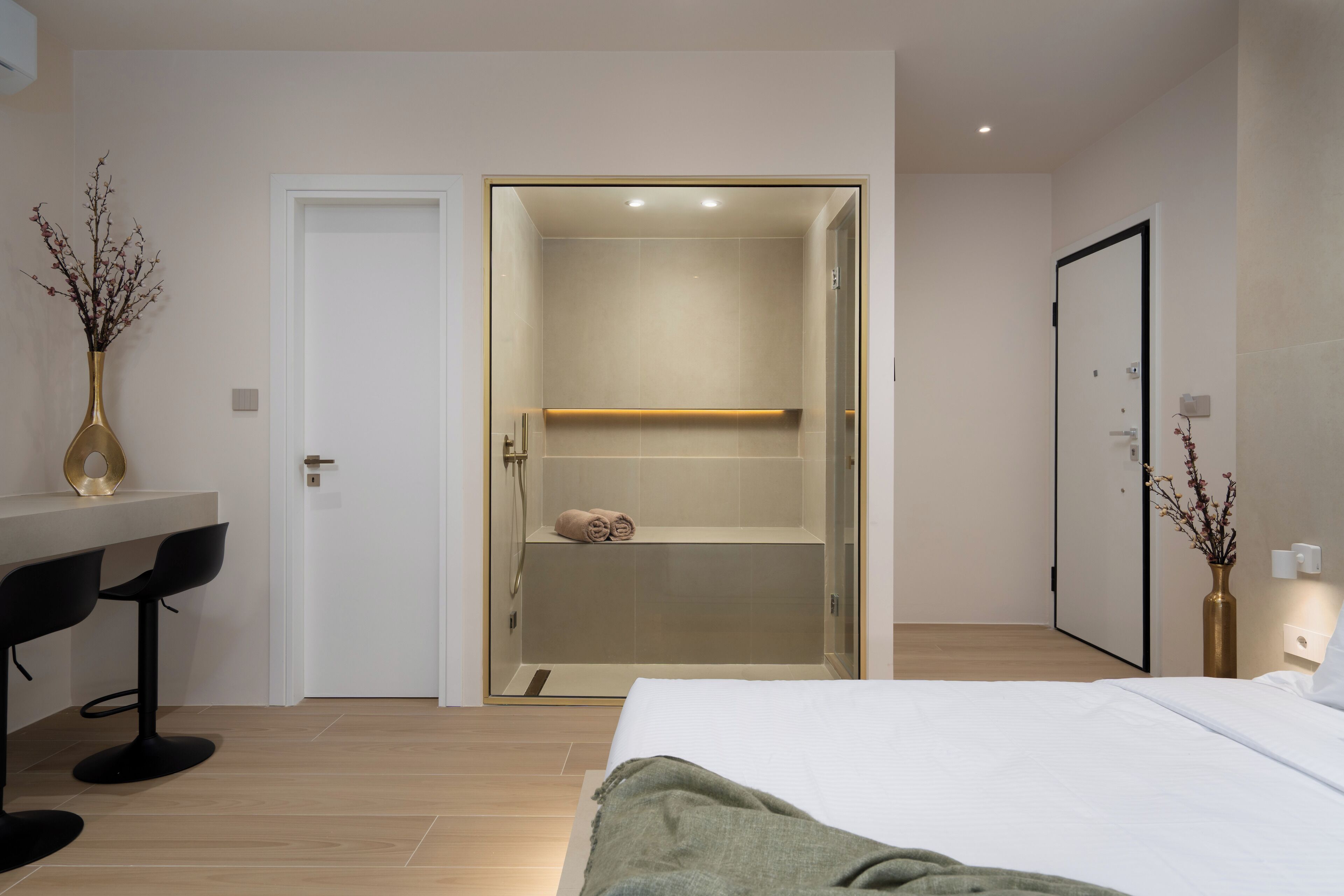 Ein modernes Hotelzimmer mit Bett, Duschbereich, einer kleinen Sitzecke mit Stühlen und einem Schreibtisch.